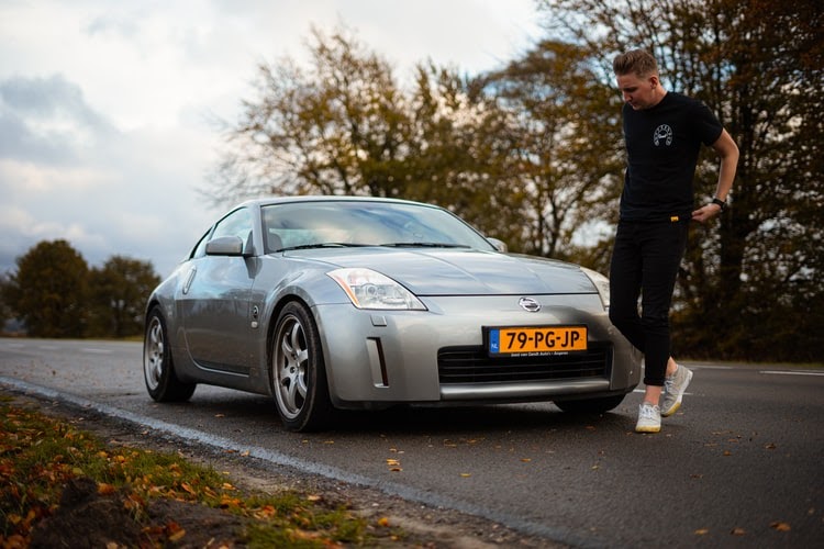 man posing in front of a Nissan 350Z